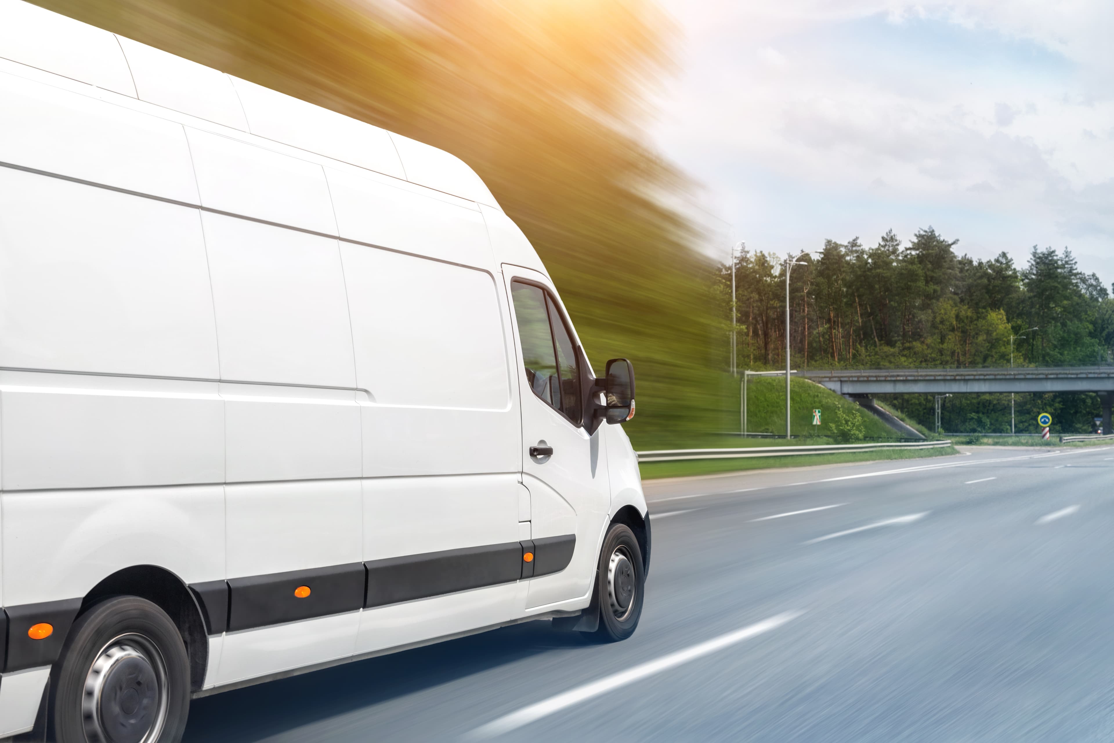 White delivery van driving on a road, motion blur