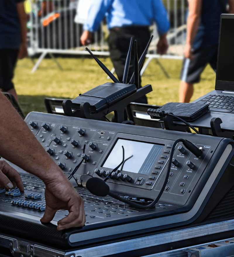 Remote-control operator panel with joysticks, person's legs visible outdoors (asset finance equipment)