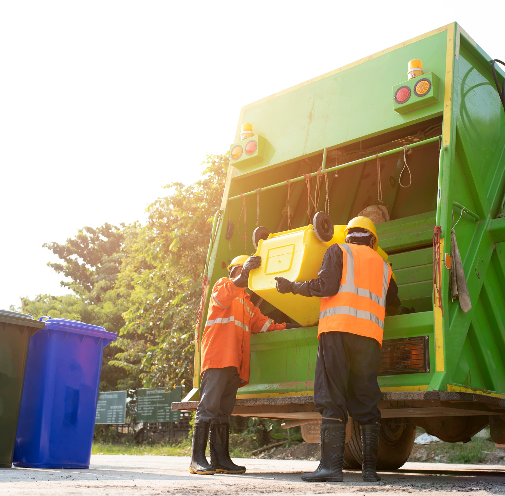 Workers in high-visibility jackets loading a green waste collection truck