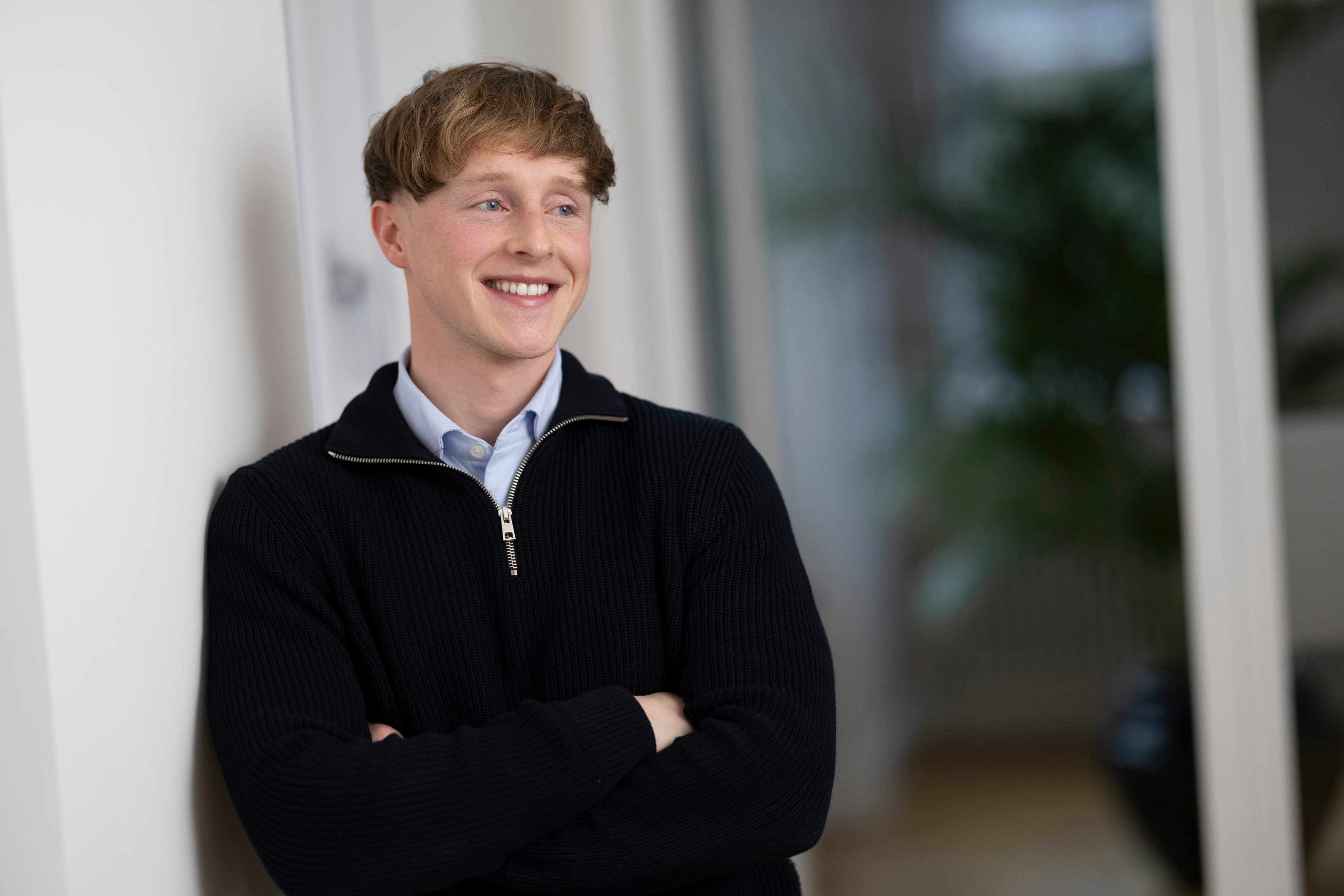 Harry — young man with strawberry-blonde hair, dark zip cardigan, smiling in office setting