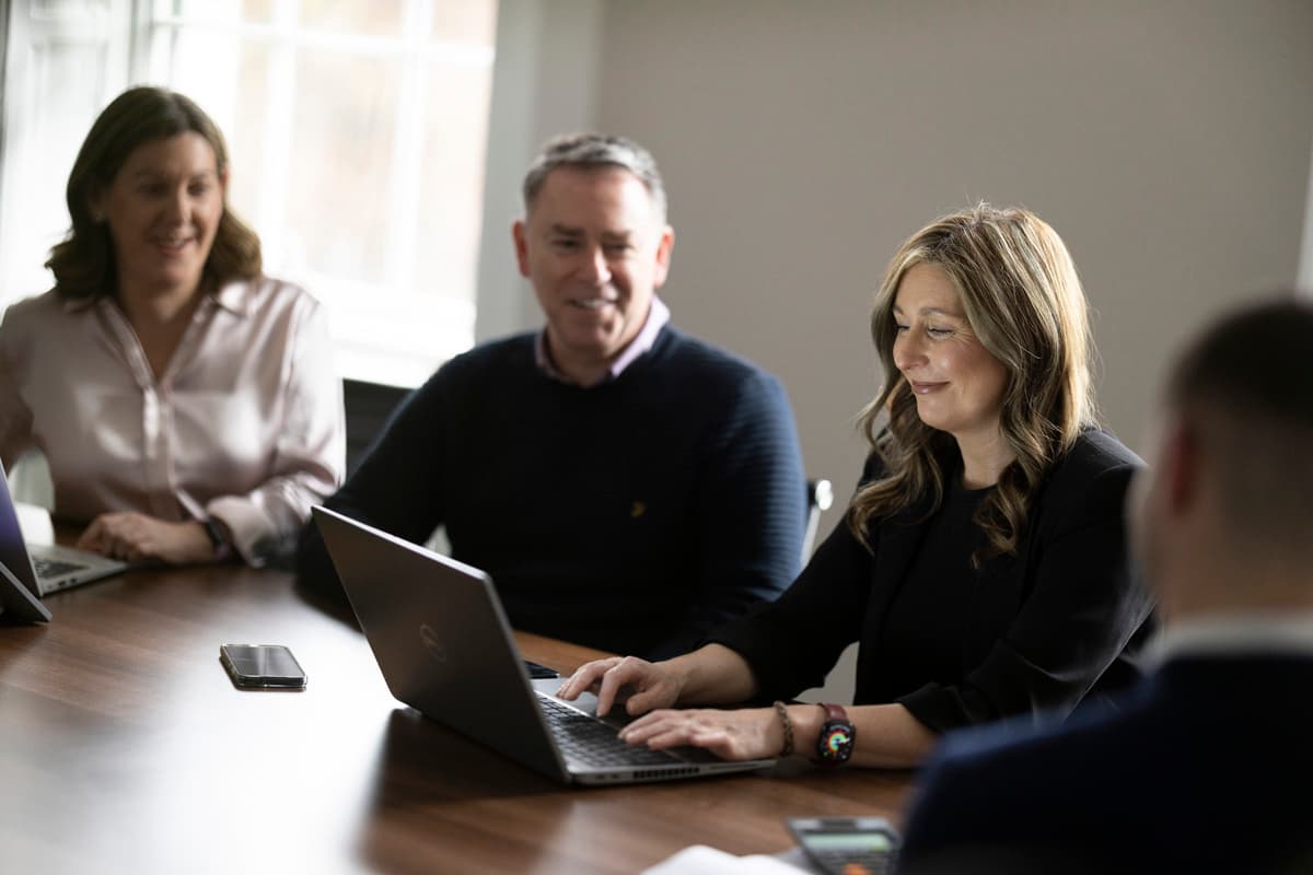 Man with laptop in a meeting, woman blurred beside him