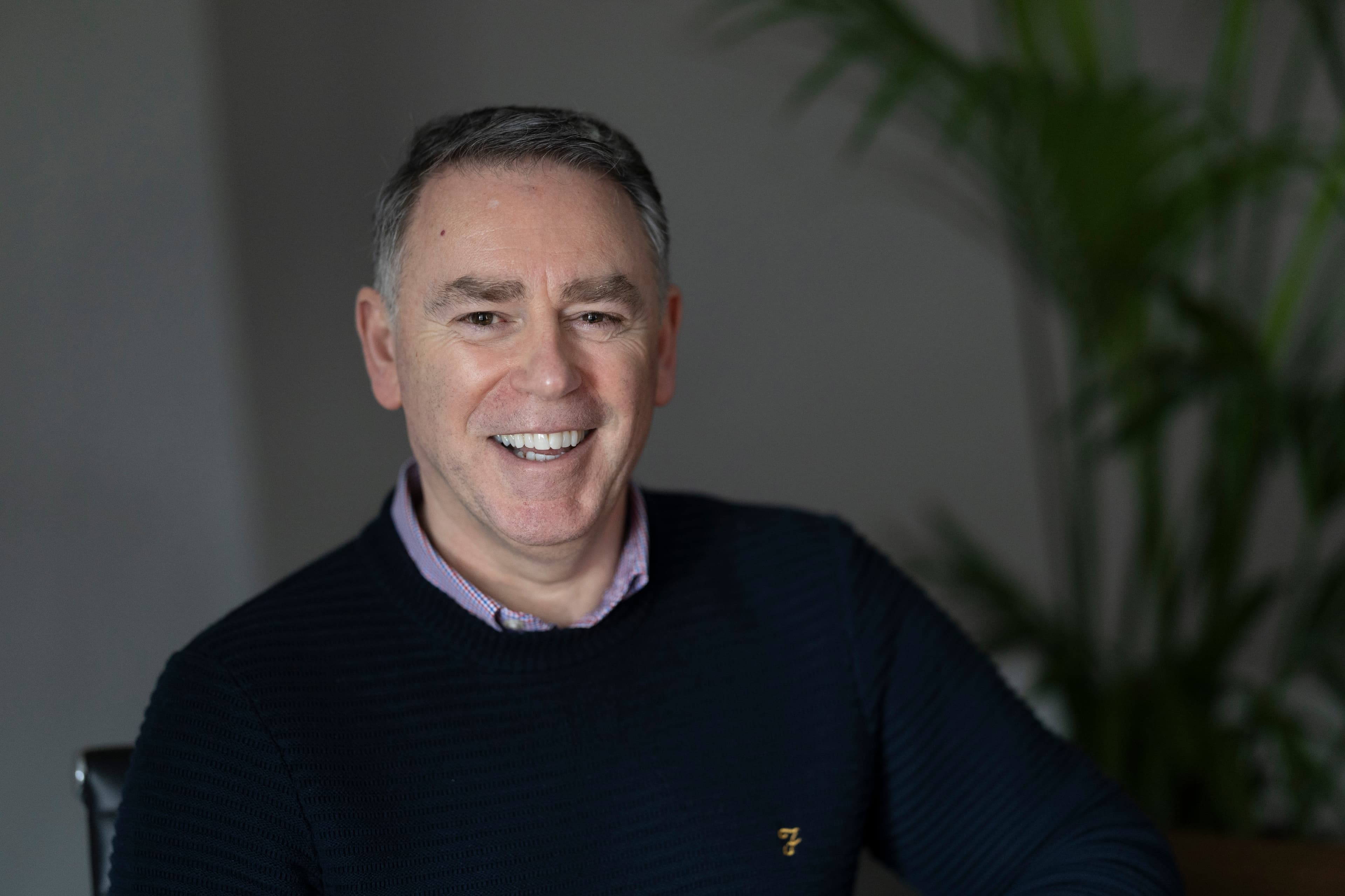 Paul — man with grey hair, dark jumper, laughing/smiling broadly in office