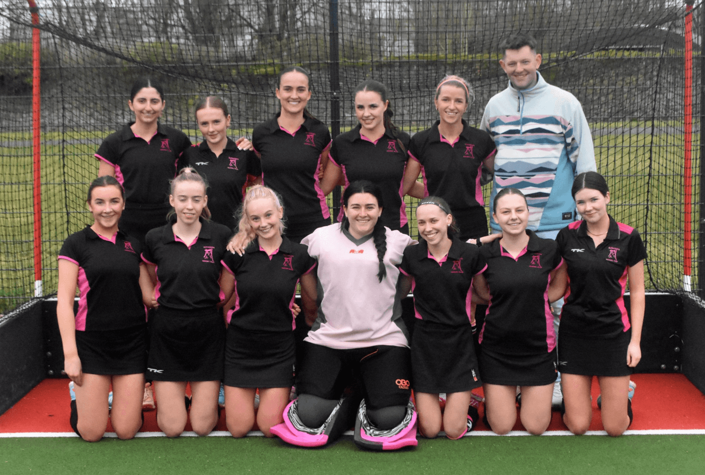 Group of female hockey team members posing together outdoors