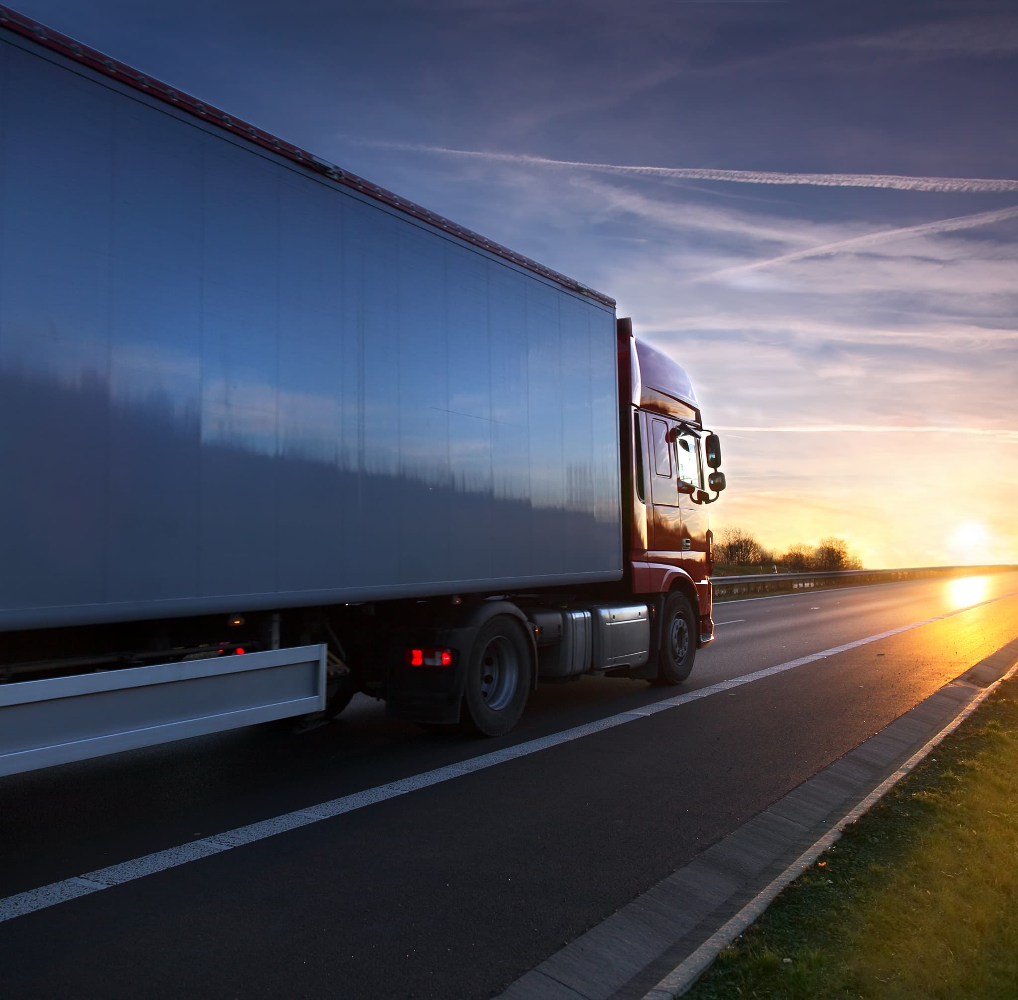 Truck driving on a road at sunset with motion blur