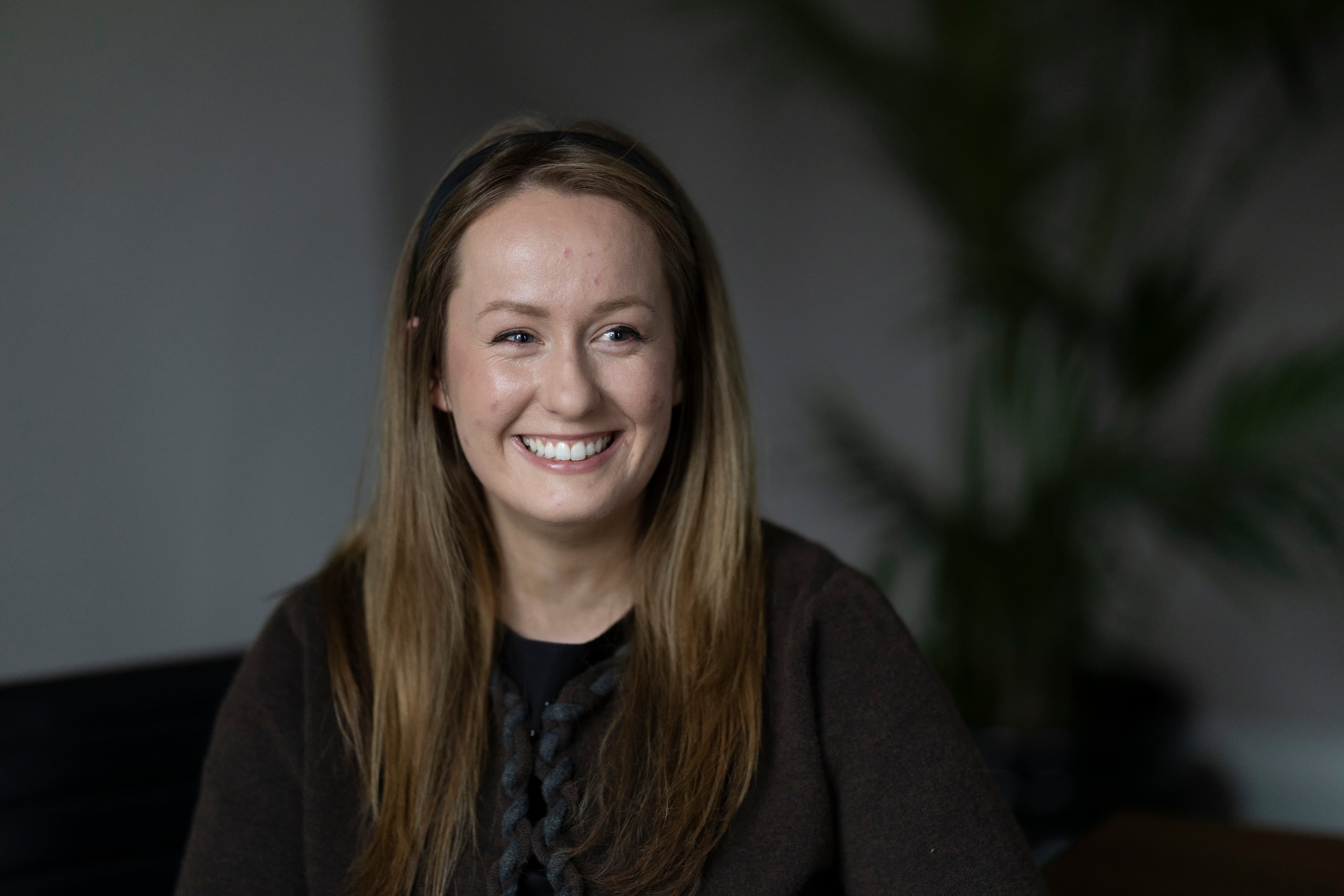 Lydia 2 — woman with long brown hair, dark top, smiling, office setting