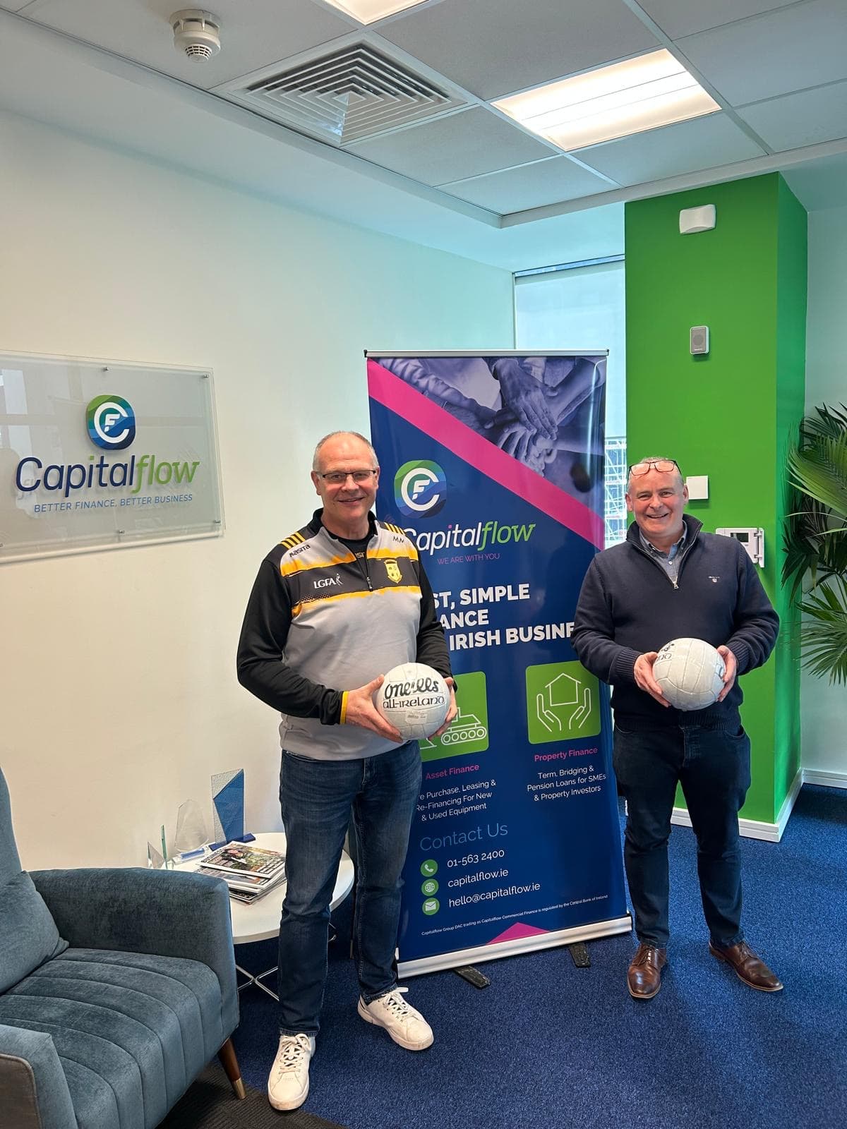 Capitalflow team members standing together in front of a branded presentation screen